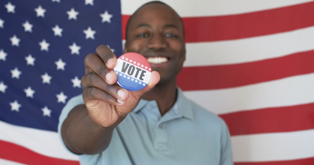 Young Man Holding 'Vote' Button in Front of American Flag