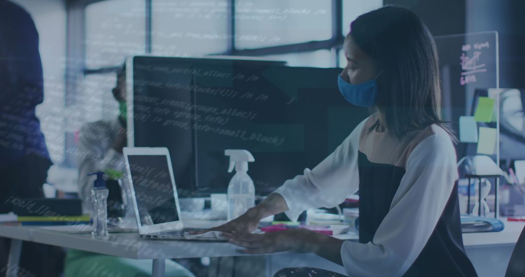 Businesswoman in Face Mask Analyzing Data on Laptop in Modern Office