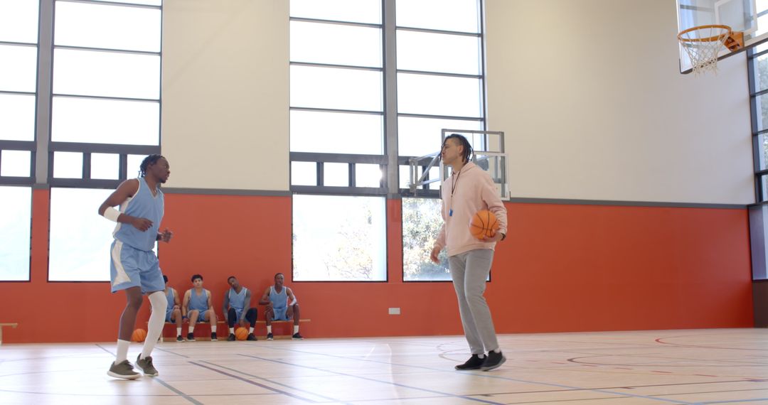 Basketball Player Practicing Dribbling with Coach in Gym