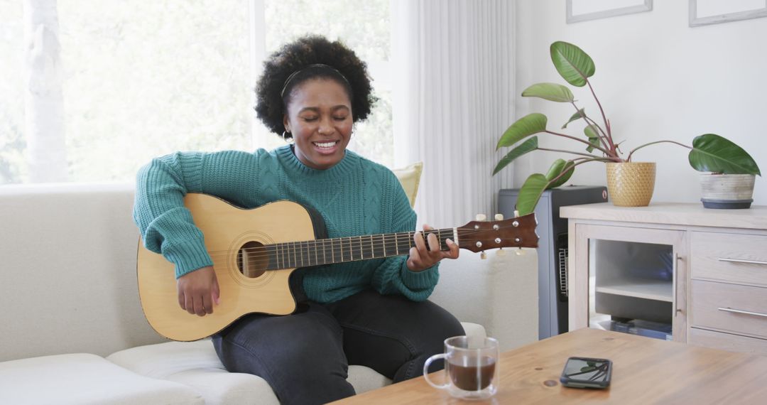 Smiling Woman Playing Acoustic Guitar in Cozy Living Room - Free Images, Stock Photos and Pictures on Pikwizard.com