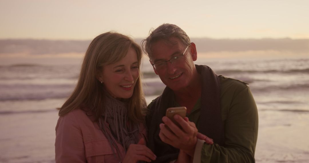 Senior Couple Enjoying Sunset on Beach with Smartphone