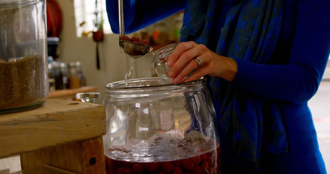 Person Pouring Liquid into Glass Jar with Red Berries - Free Images, Stock Photos and Pictures on Pikwizard.com