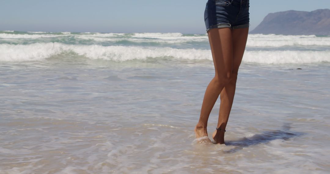 Woman's Legs in Shorts Standing on the Beach Near Waves - Free Images, Stock Photos and Pictures on Pikwizard.com