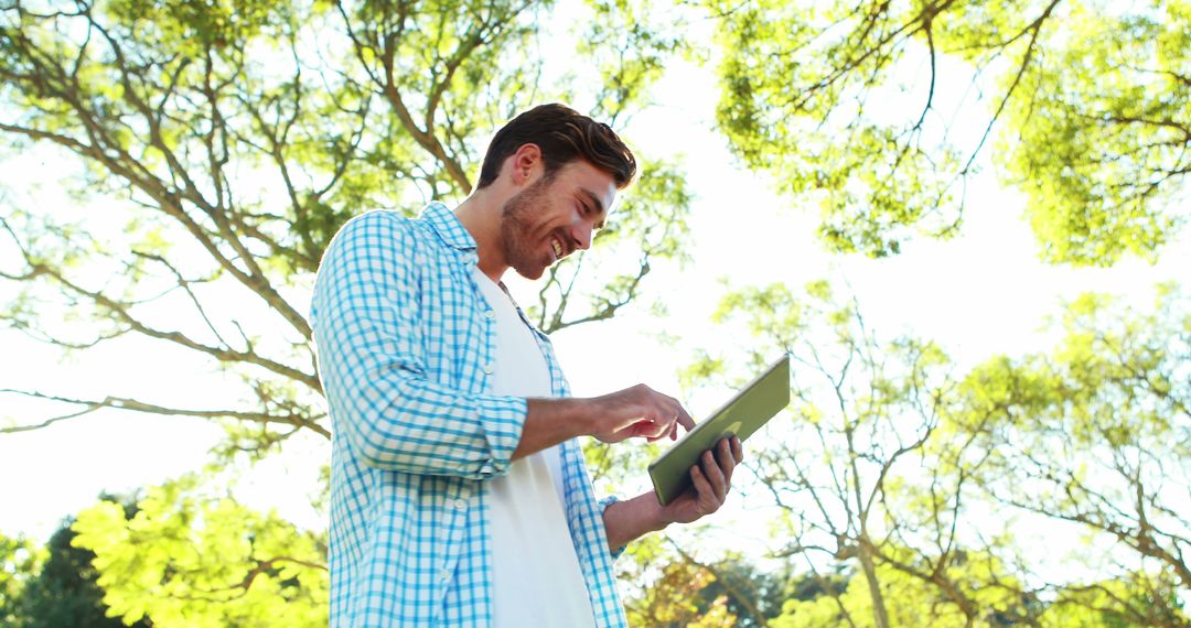 Smiling Man Using Tablet Outdoors on Sunny Day - Free Images, Stock Photos and Pictures on Pikwizard.com