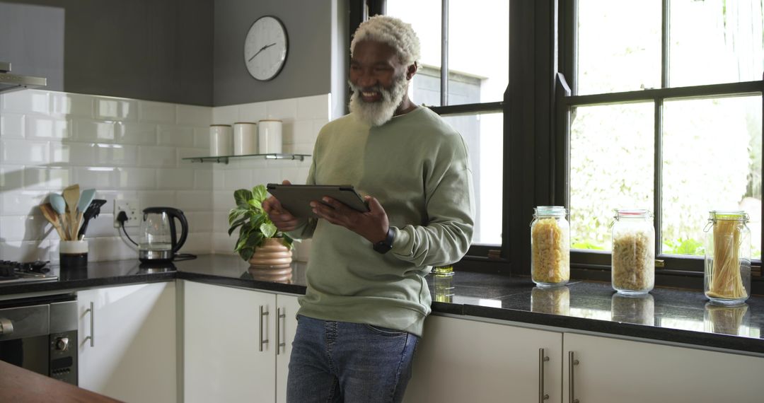 Mature Man Using Tablet in Modern Kitchen with Pasta Jars