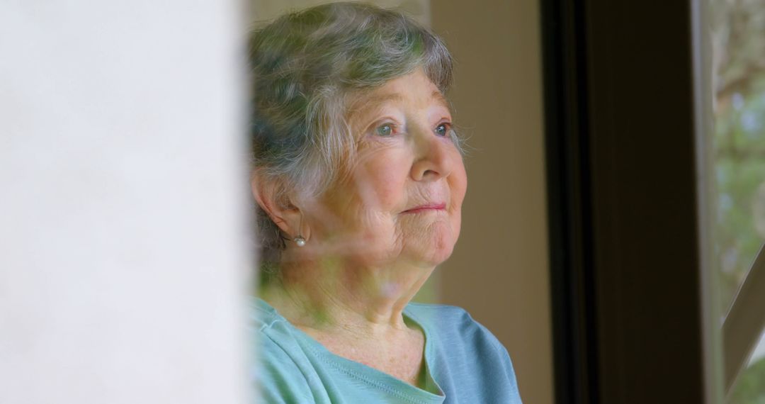 Senior Caucasian woman looks thoughtfully out a window, with copy space - Free Images, Stock Photos and Pictures on Pikwizard.com