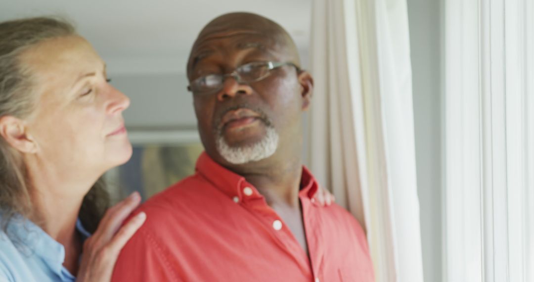 Happy Senior Couple Embracing in Living Room by Window