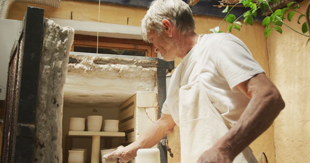 Senior Potter Operating Kiln in Workshop Environment