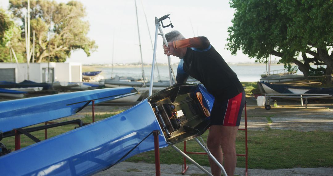 Man Repairing Rowing Boat Near Lake Outdoors - Free Images, Stock Photos and Pictures on Pikwizard.com