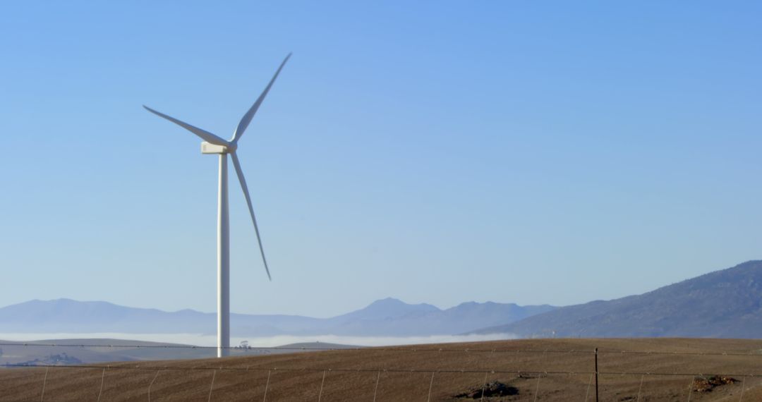 Wind Turbine on Barren Field with Mountain Range Background - Free Images, Stock Photos and Pictures on Pikwizard.com