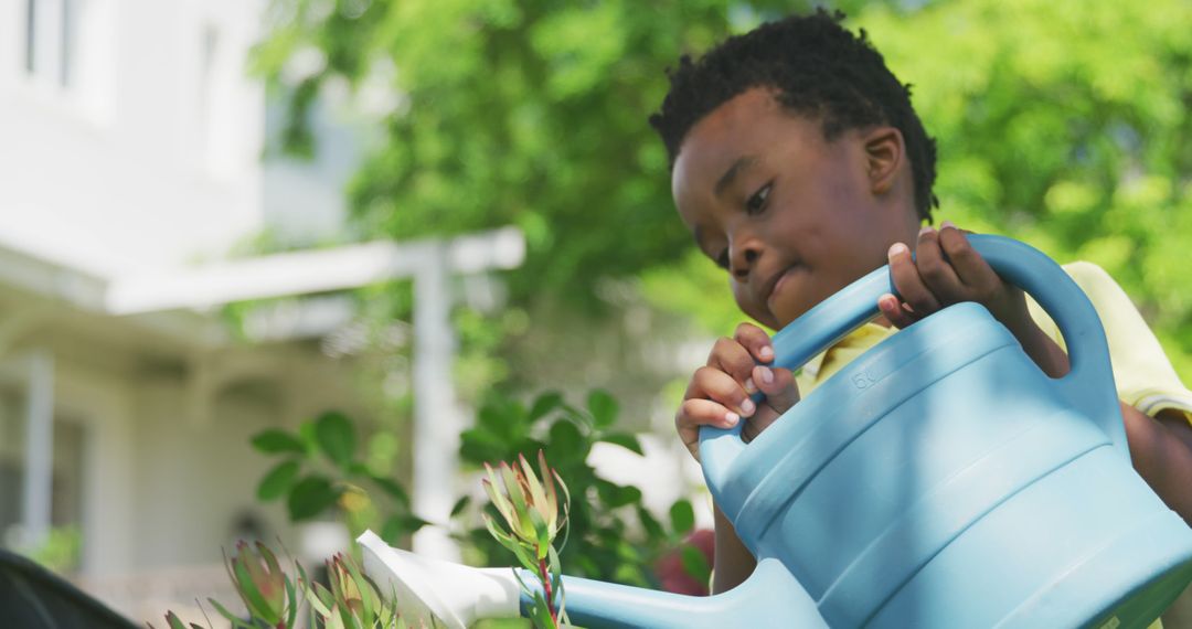 Young Black Boy Watering Plants with Blue Watering Can in Backyard - Free Images, Stock Photos and Pictures on Pikwizard.com