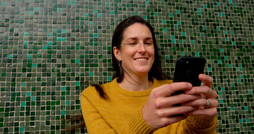 Smiling Woman Using Smartphone Against Checkered Wall - Free Images, Stock Photos and Pictures on Pikwizard.com