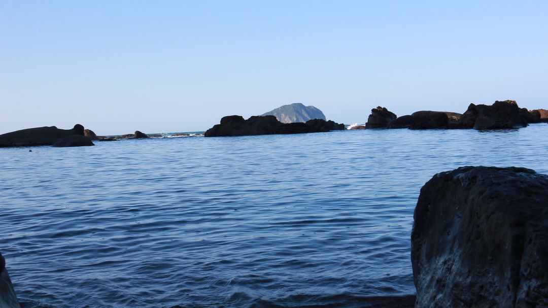 Idyllic Rocky Coastline with Clear Blue Sea and Distant Island - Free Images, Stock Photos and Pictures on Pikwizard.com