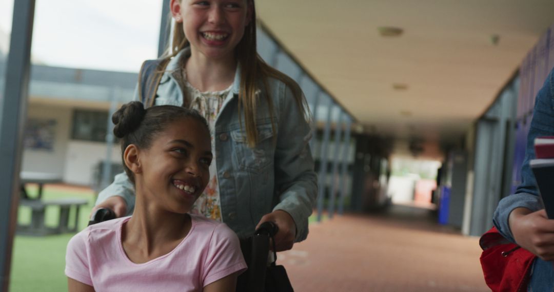 Two Happy Girls in a School Hallway, One Pushing the Other in a Wheelchair - Free Images, Stock Photos and Pictures on Pikwizard.com