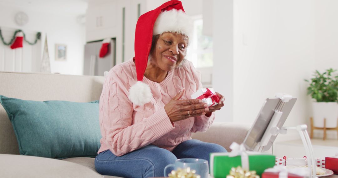 Senior Woman Wearing Santa Hat Video Calling Christmas and Showing Wrapped Gift - Free Images, Stock Photos and Pictures on Pikwizard.com