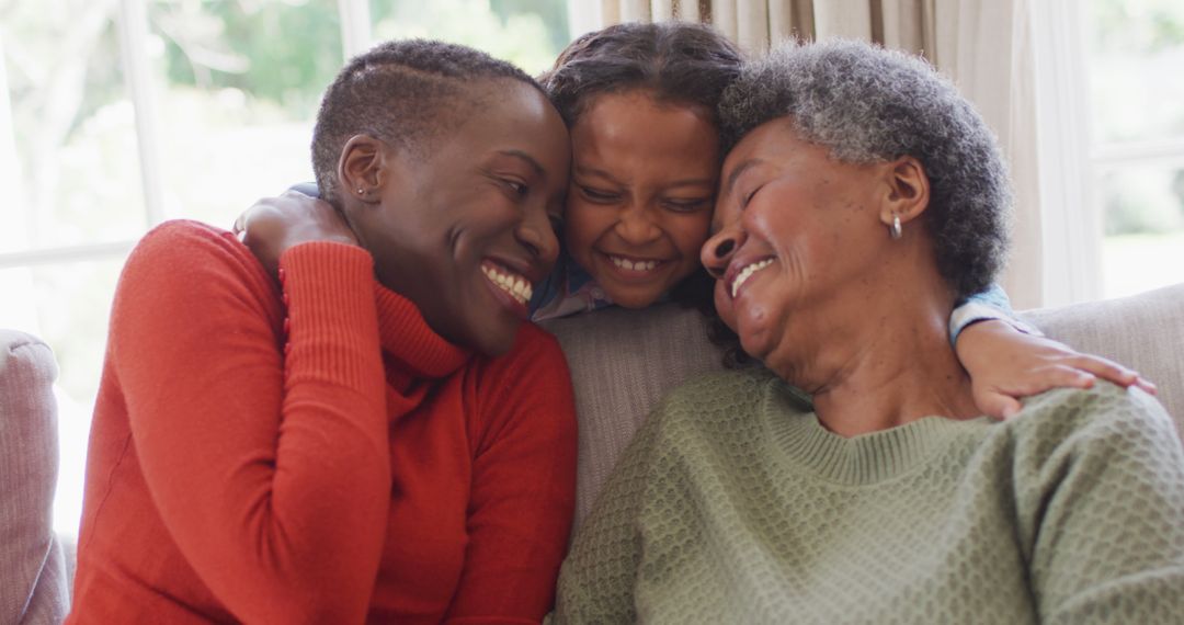 Image of smiling african american mother, daughter and grandmother sitting hugging in living room - Free Images, Stock Photos and Pictures on Pikwizard.com