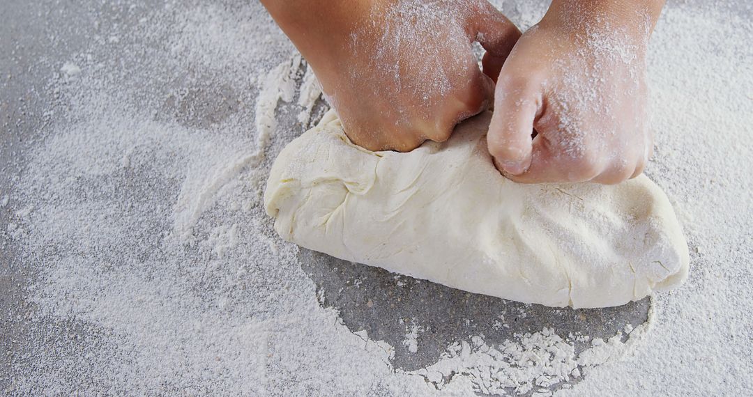 Hands Kneading Dough on Floured Surface