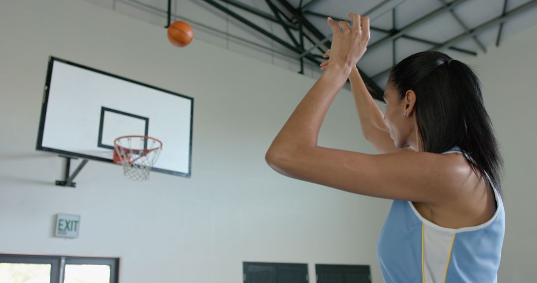 Female Basketball Player Focused on Shooting Towards Hoop in Gym