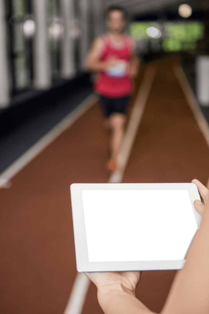 Transparent Digital Tablet Overlooking Track Runner Training Indoors