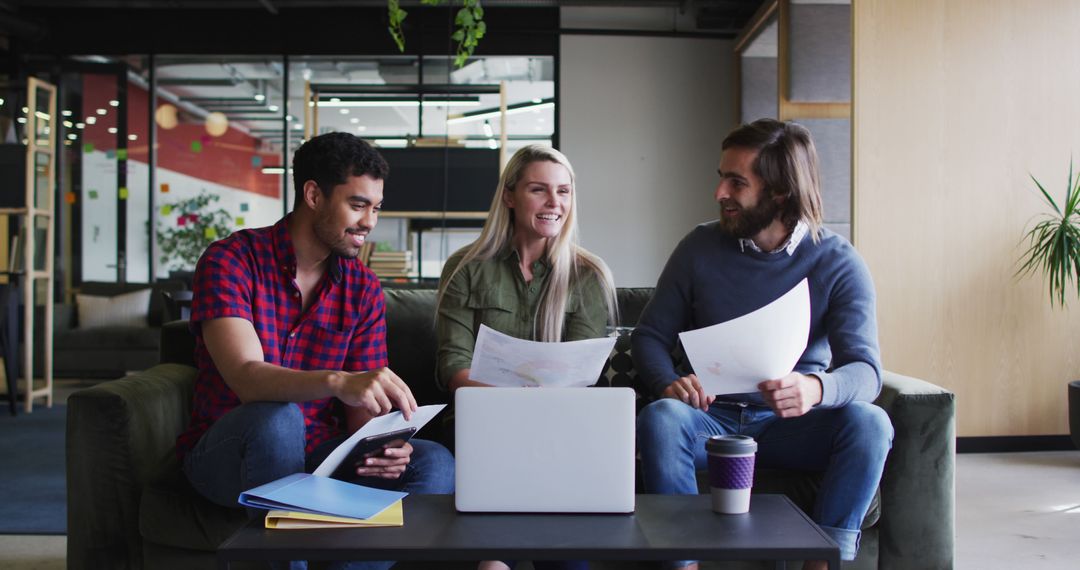 Team Collaboration in Modern Office with Laptops and Paperwork