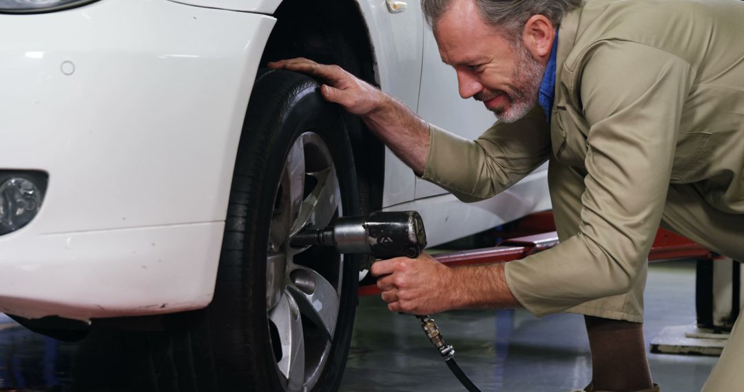 Experienced Mechanic Working on Car Tire with Power Tool - Free Images, Stock Photos and Pictures on Pikwizard.com