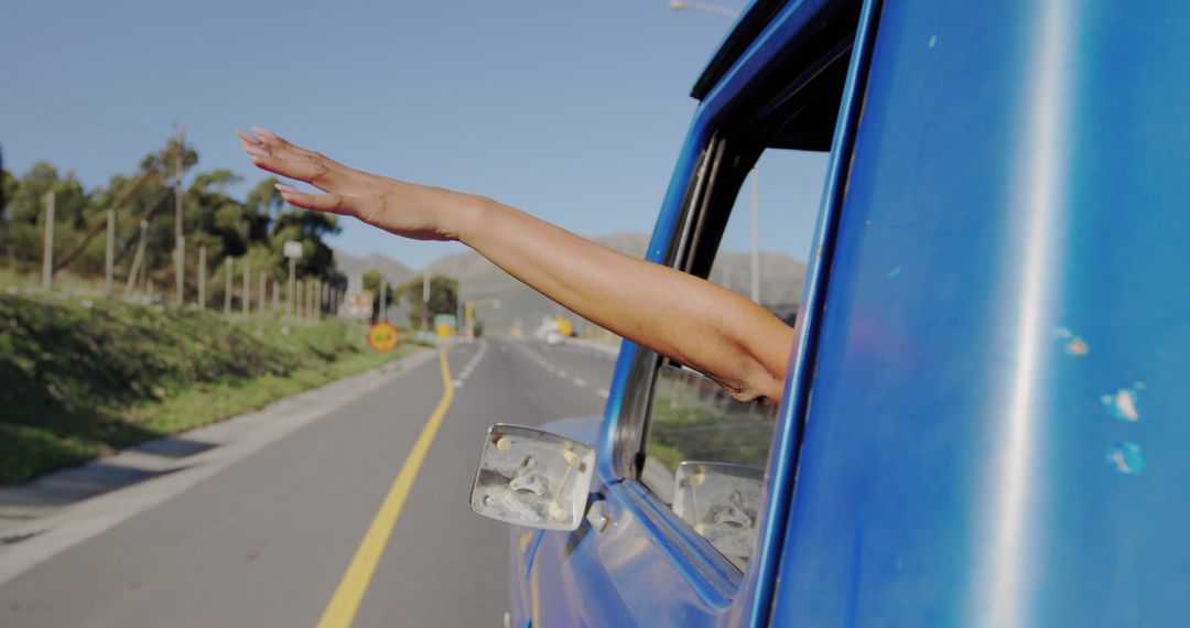 Person Relaxing with Hand Out Car Window on Open Road - Free Images, Stock Photos and Pictures on Pikwizard.com