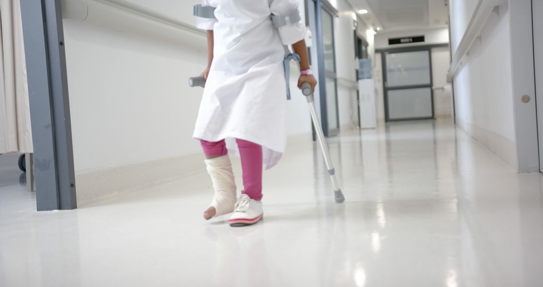 Midsection of african american girl patient with crutches walking in corridor in hospital - Free Images, Stock Photos and Pictures on Pikwizard.com