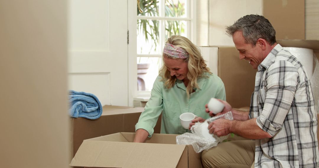 A middle-aged Caucasian man and woman are unpacking items from a box, with copy space - Free Images, Stock Photos and Pictures on Pikwizard.com