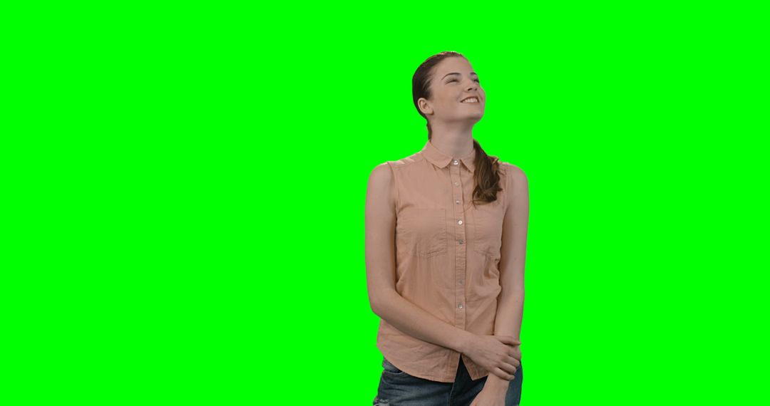 Young woman smiling and looking up against green screen background - Free Images, Stock Photos and Pictures on Pikwizard.com