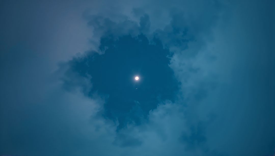 Full Moon Illuminating Circular Gap in Night Clouds
