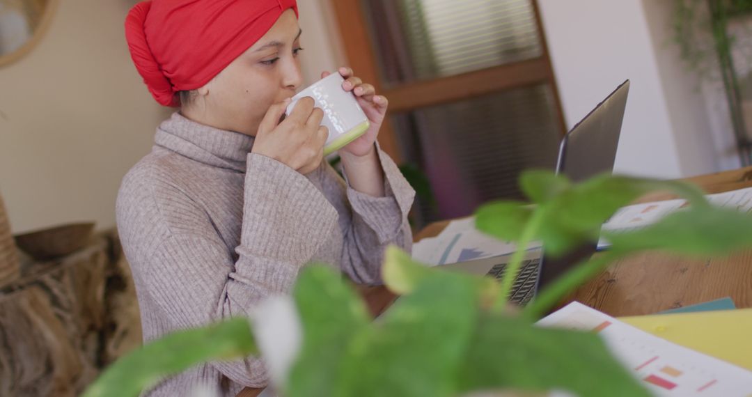 Woman with Red Headscarf Working from Home on Laptop while Drinking Coffee - Free Images, Stock Photos and Pictures on Pikwizard.com