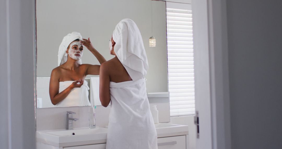 Woman in Towel Applying Facial Mask in Bathroom Mirror - Free Images, Stock Photos and Pictures on Pikwizard.com