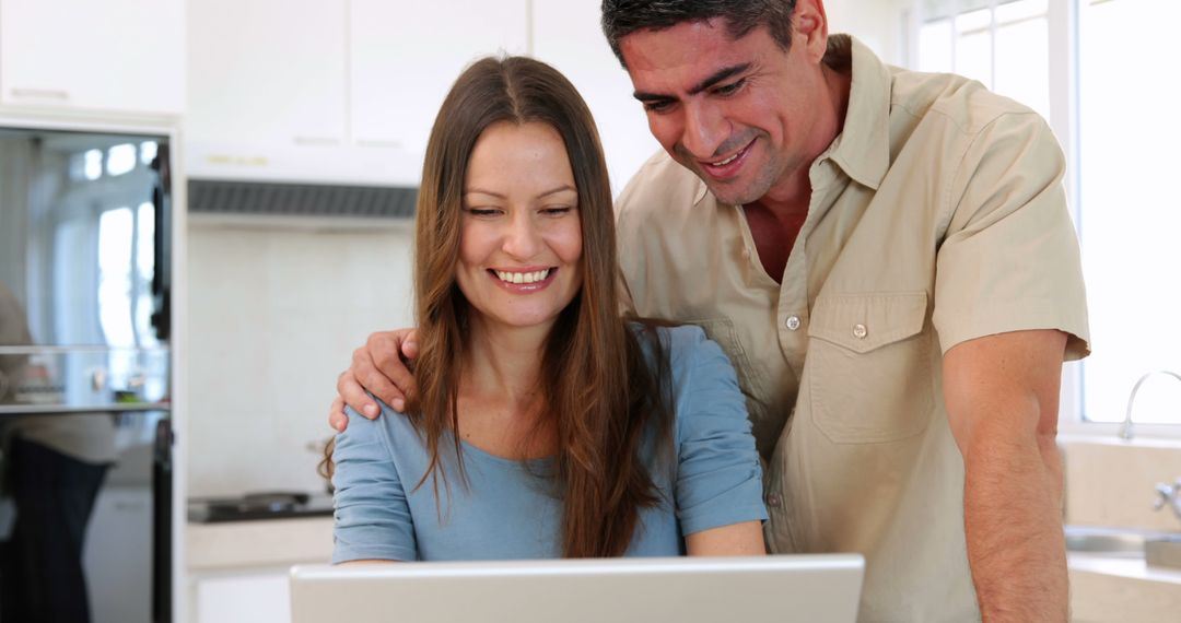 Happy Couple Smiling Browsing Laptop in Kitchen