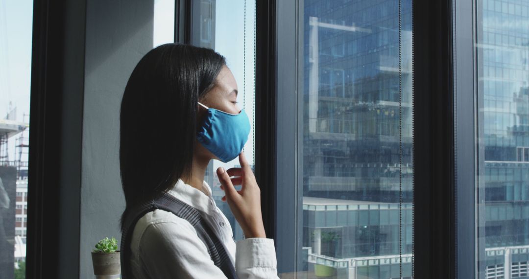 Woman in Blue Face Mask Looking Out City Window During Daytime - Free Images, Stock Photos and Pictures on Pikwizard.com