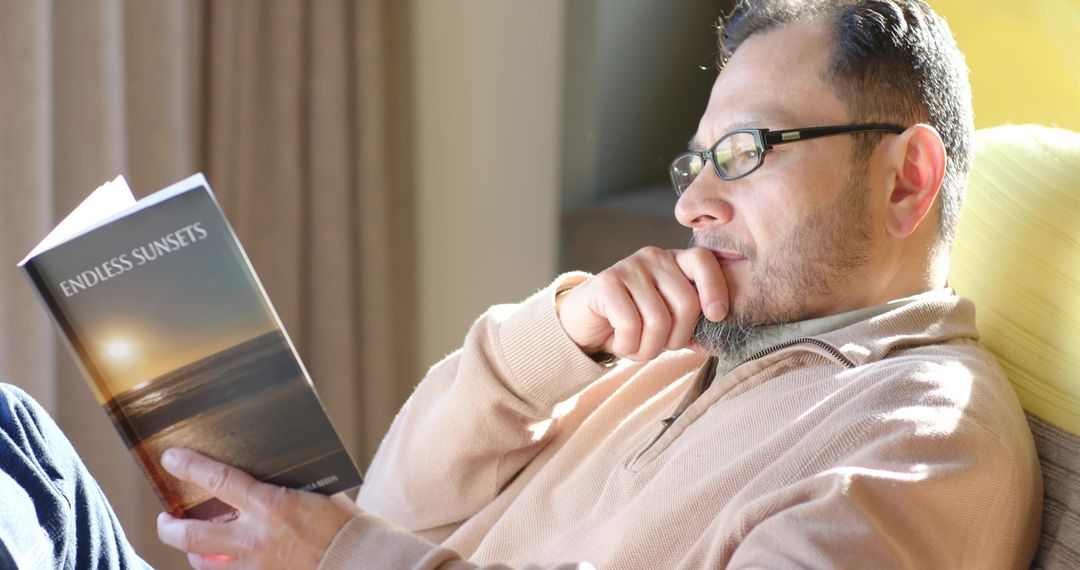 Man Relaxing with Book Sunlit Indoors During Leisure Time