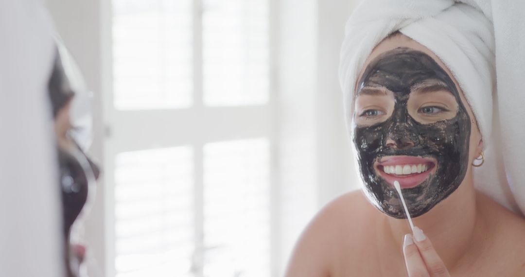 Woman Applying Charcoal Face Mask and Smiling in Mirror - Free Images, Stock Photos and Pictures on Pikwizard.com