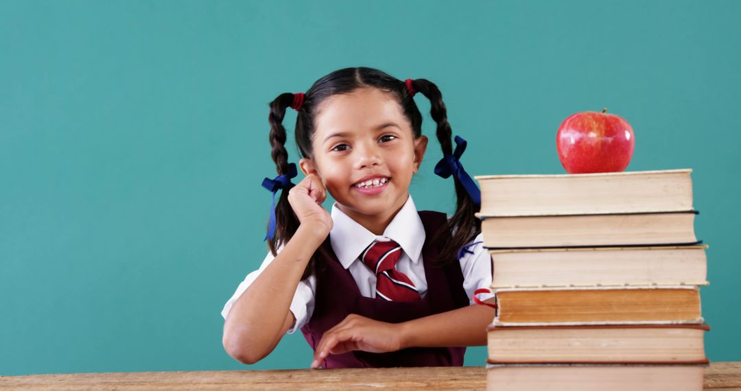 Cheerful Schoolgirl with Braids Smiling Next to Books and Apple