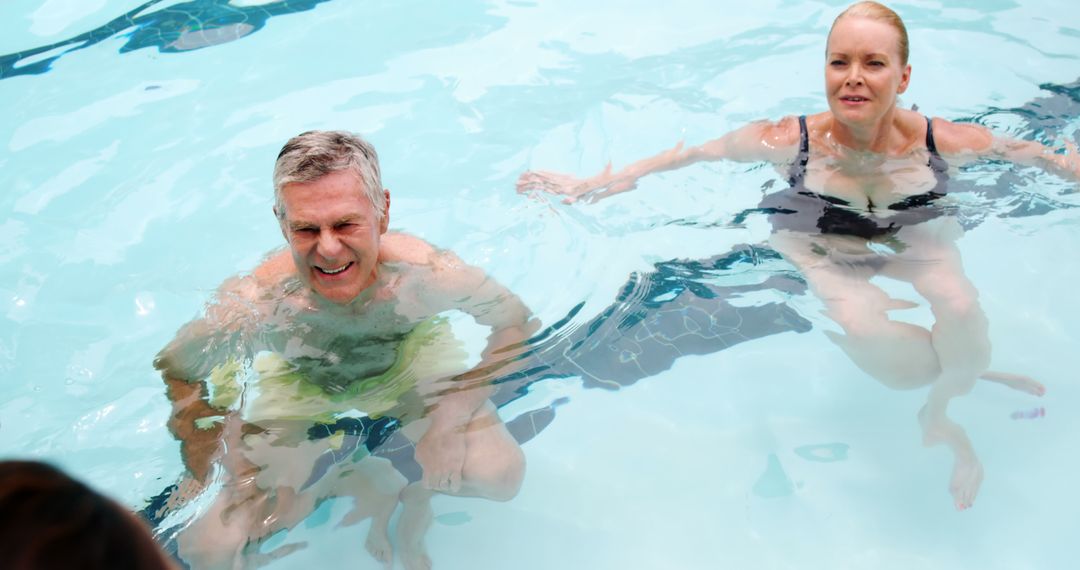 Smiling Senior Couple Enjoying Leisurely Swim in Pool - Free Images, Stock Photos and Pictures on Pikwizard.com