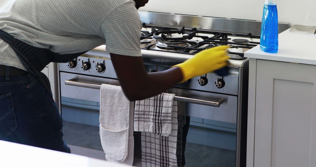 Person Cleaning Kitchen Stove with Yellow Gloves - Free Images, Stock Photos and Pictures on Pikwizard.com