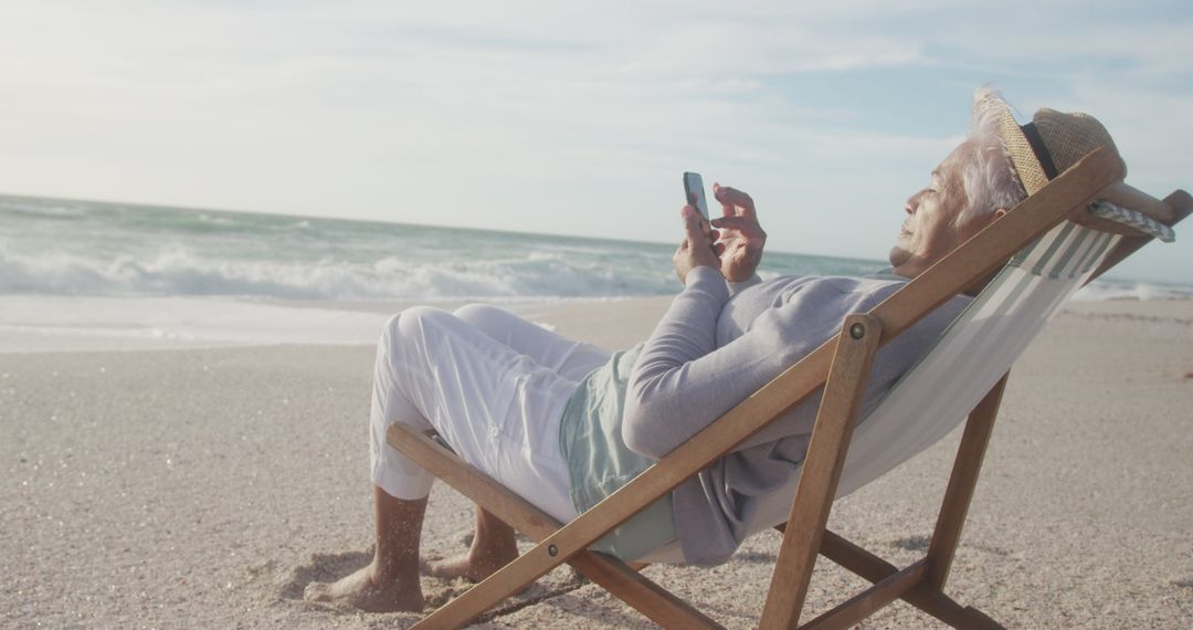 Senior Woman Engaging with Technology on Serene Beach