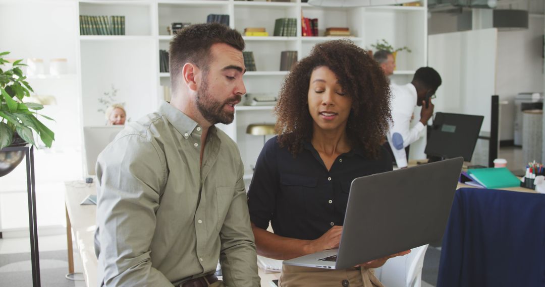 Highly focused team discusses over their laptop screen in modern office