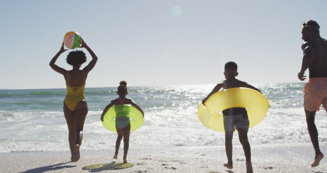 African American Family Having Fun at Beach with Inflatable Tubes - Free Images, Stock Photos and Pictures on Pikwizard.com