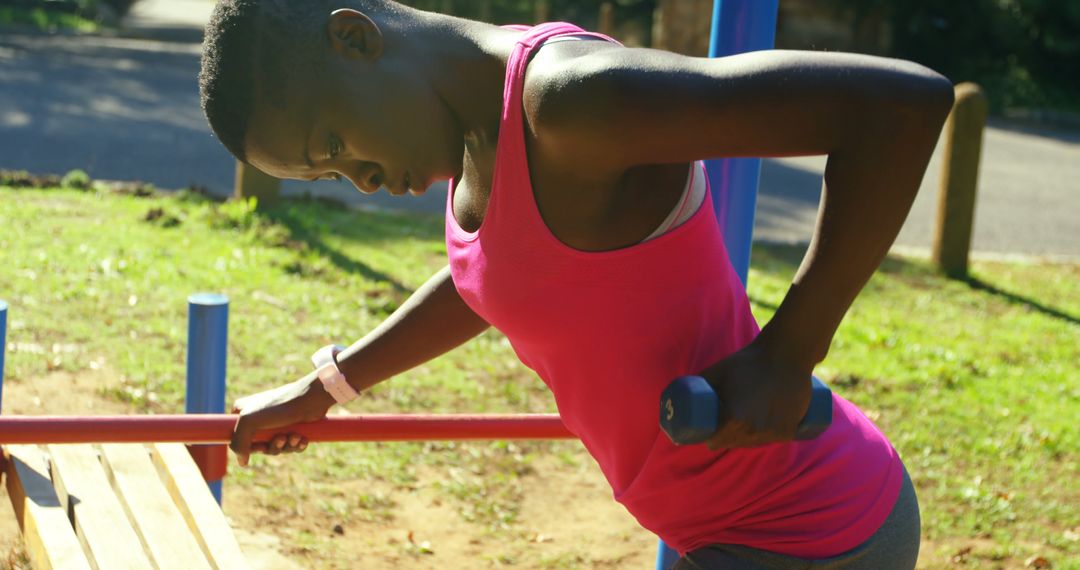 Young Woman in Pink Top Exercising with Dumbbells Outdoors - Free Images, Stock Photos and Pictures on Pikwizard.com