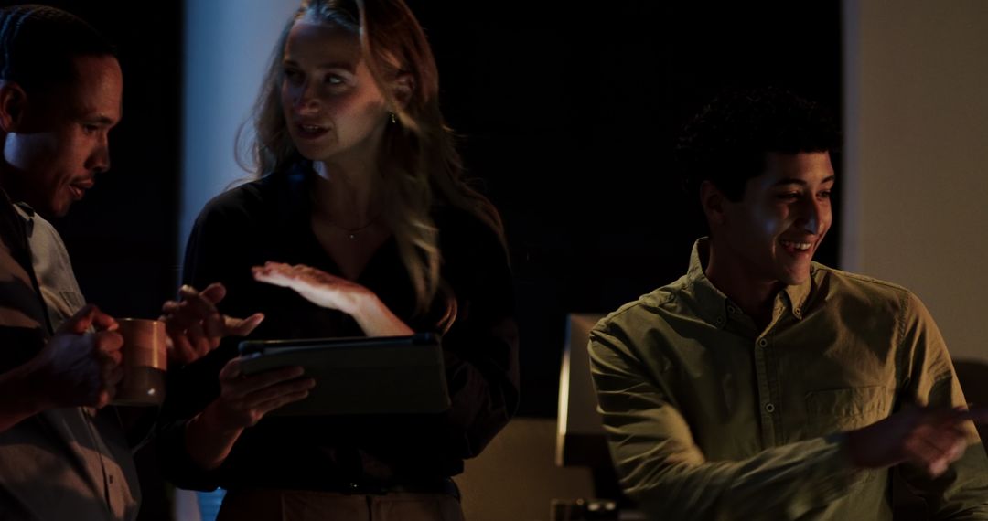 Diverse Colleagues Collaborating with Technology in Late-Night Office Session