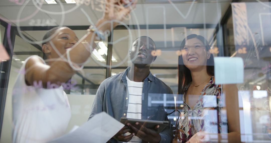Diverse Team Collaborating with Transparent Board in Office