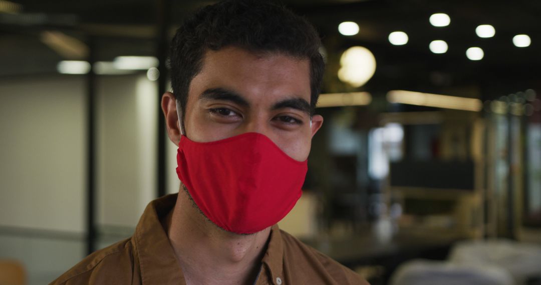 Young man wearing red face mask inside office workspace - Free Images, Stock Photos and Pictures on Pikwizard.com