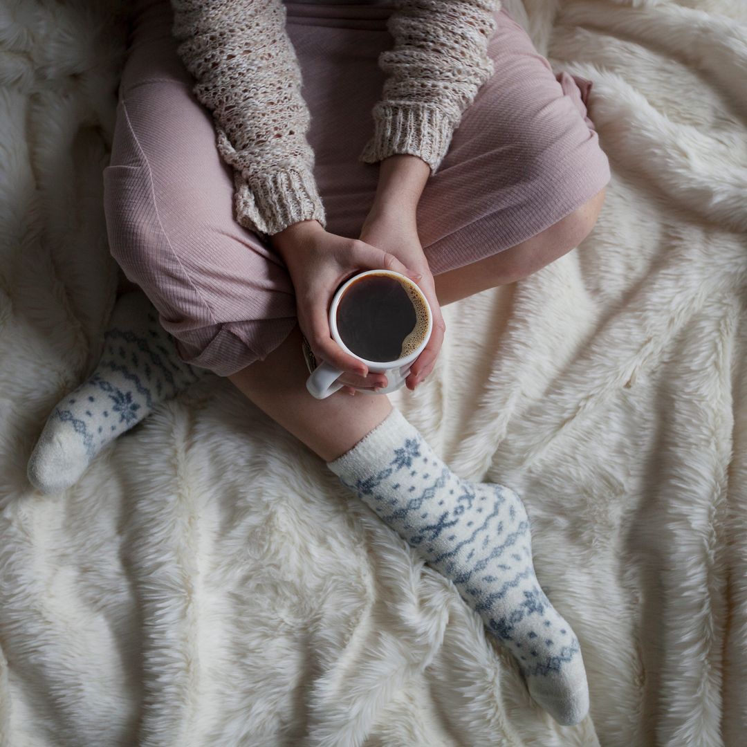 Cozy Relaxing Woman Holding Coffee Mug in Bed Wearing Warm Socks - Free Images, Stock Photos and Pictures on Pikwizard.com