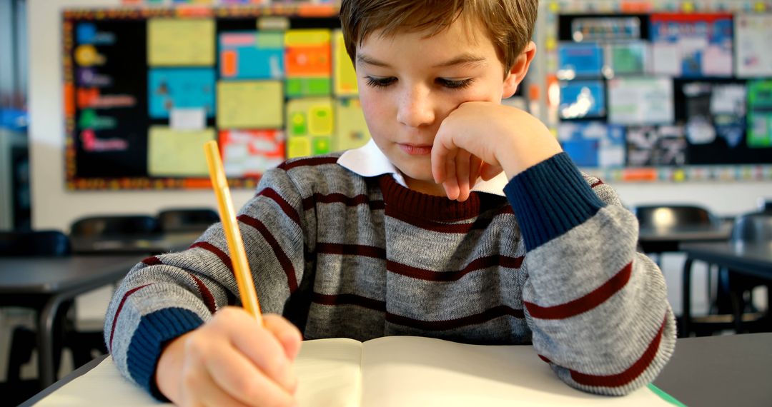 Young Student Writing in Notebook at Classroom Desk - Free Images, Stock Photos and Pictures on Pikwizard.com