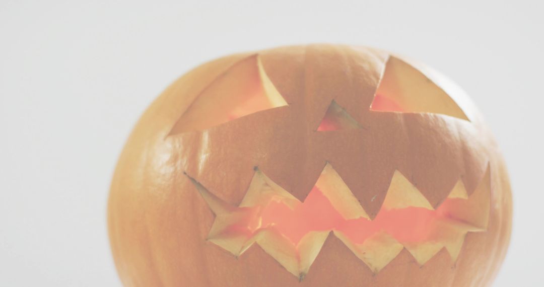 Glowing Jack-o'-Lantern with Triangular Eyes and Jagged Mouth on Light Gray Backdrop