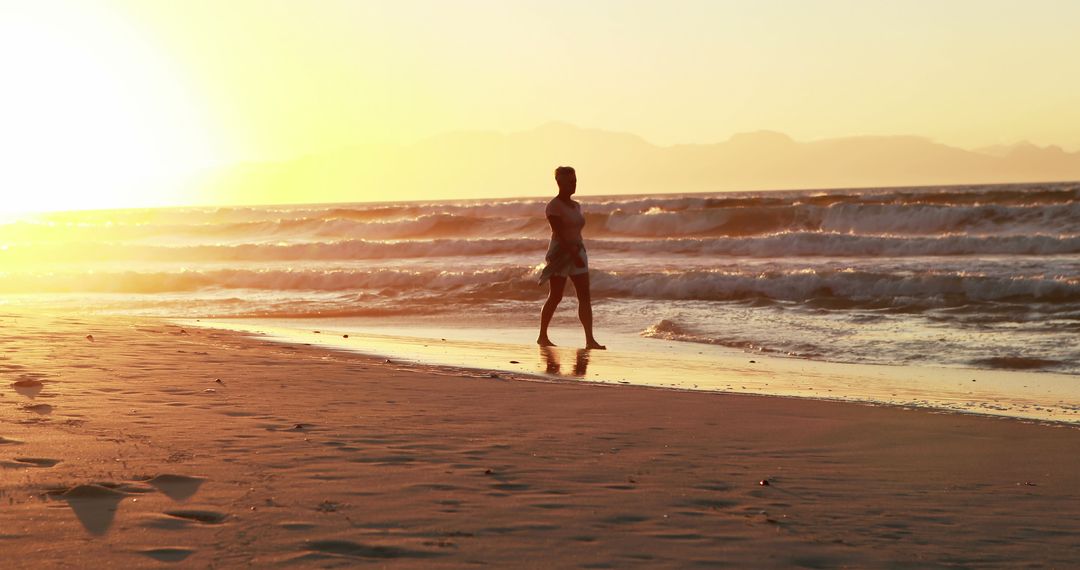 Woman Walking on Beach at Sunset with Gentle Waves - Free Images, Stock Photos and Pictures on Pikwizard.com